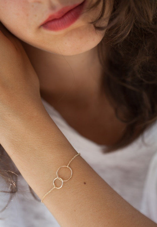 سوار نسائي من الفولاذ المقاوم للصدأ مطلي بالذهب، مزين بدائرتين متشابكتين مطروقتين.